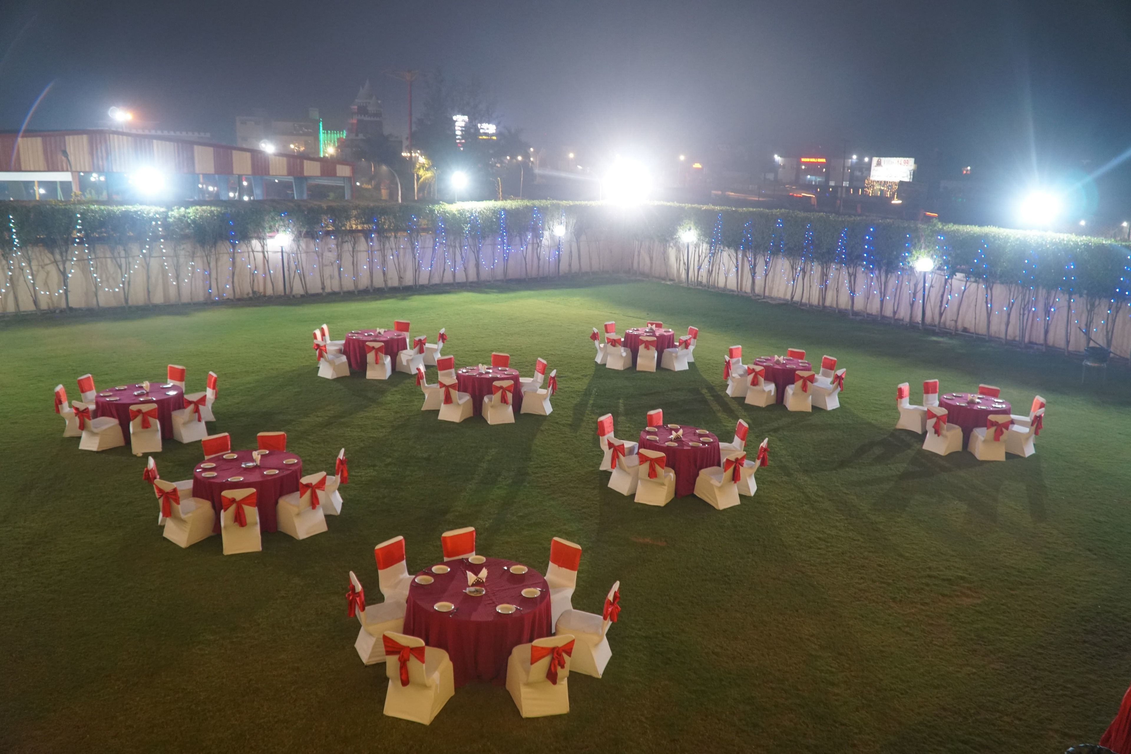 An outdoor event space with multiple round tables and chairs, arranged in a semi-circular pattern on a grassy lawn.