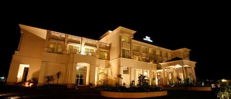 A multi-story hotel with a grand entrance, large windows, and a well-lit facade.