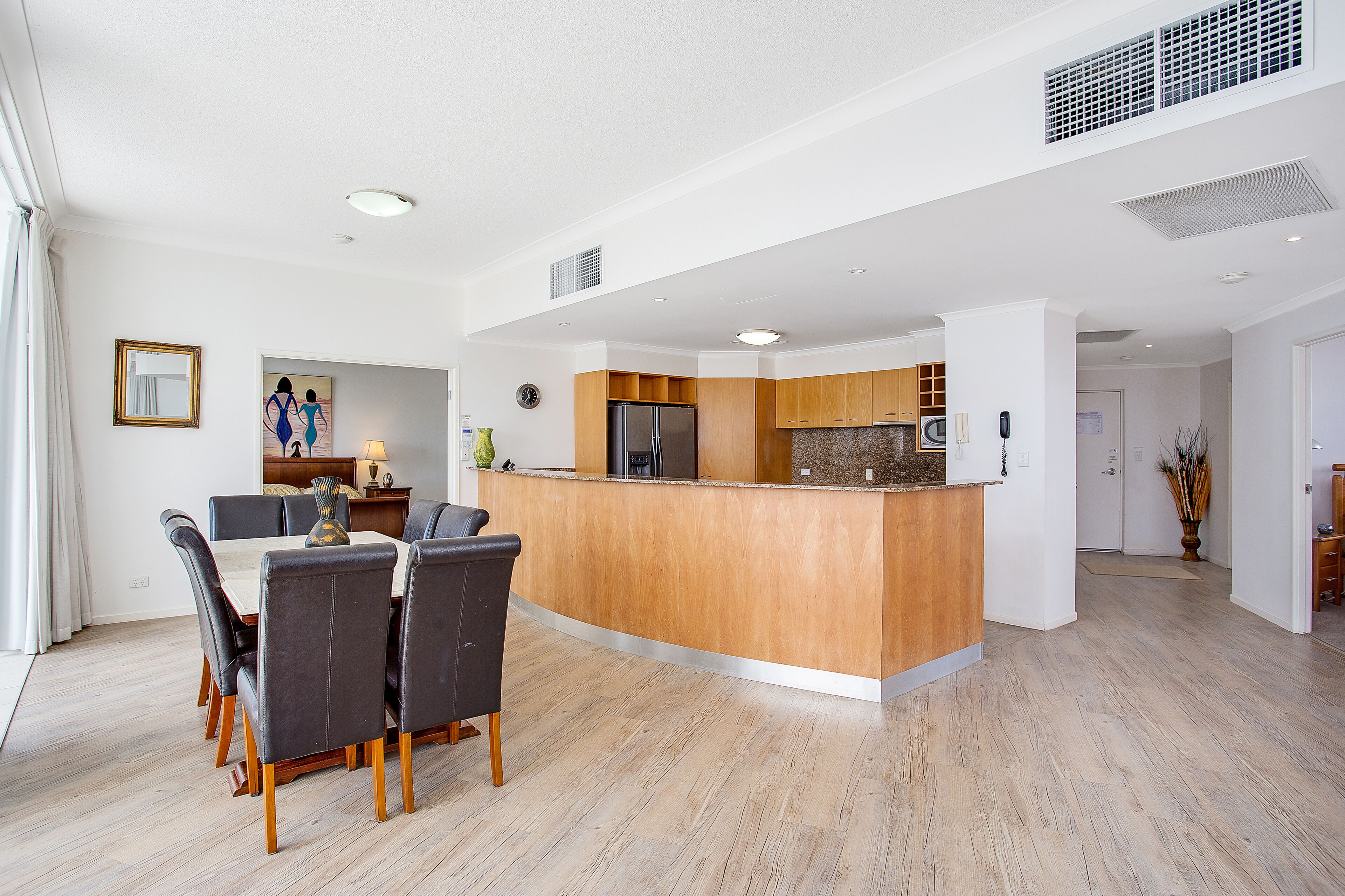 Une cuisine moderne avec des meubles en bois et un îlot central, un coin repas avec une table et des chaises, et un espace de vie avec un canapé et une table basse.