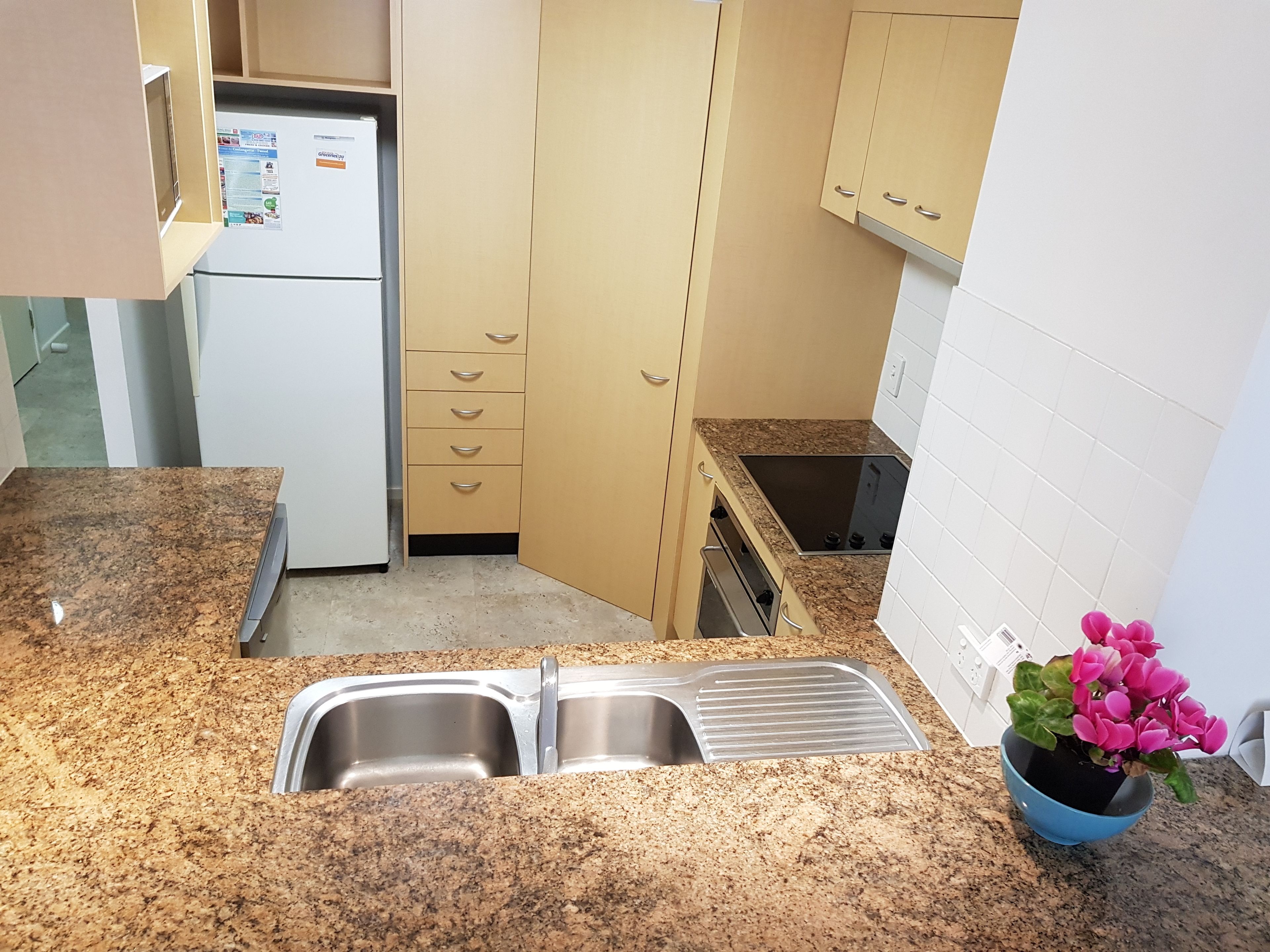 A kitchen with granite countertops, a stainless steel sink, a built-in oven, and a refrigerator.