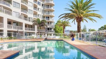 Enjoy a refreshing swim in the hotel's outdoor pool surrounded by a tiled deck and lush palm trees.