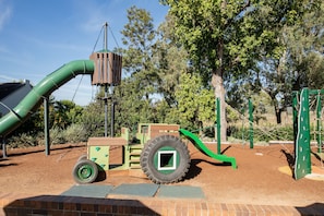 Ein Spielplatz mit Rutsche, Klettergerüsten und einer reifenartigen Kletterkonstruktion.