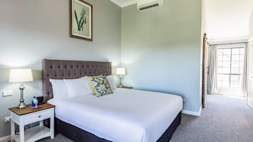 Una cama impecable con ropa blanca, un cabecero capitonado y dos lámparas de noche.