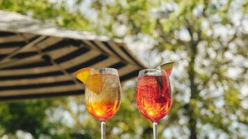 Two glasses of beverages on a balcony with a blurred background of trees.