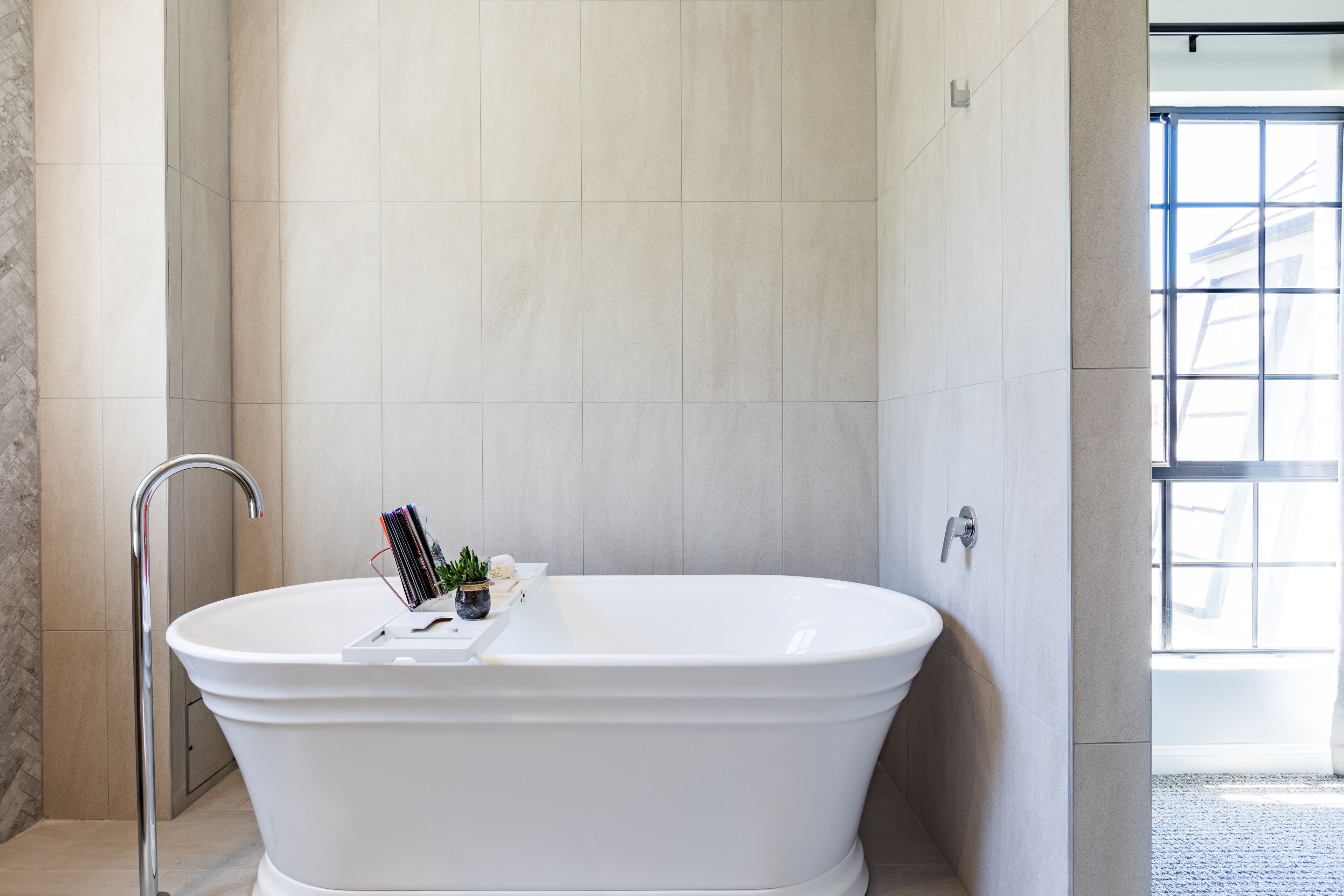 Une salle de bain moderne avec une baignoire sur pieds, un porte-serviettes et une fenêtre laissant entrer la lumière naturelle.