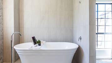Une salle de bain moderne avec une baignoire sur pieds, un porte-serviettes et une fenêtre laissant entrer la lumière naturelle.