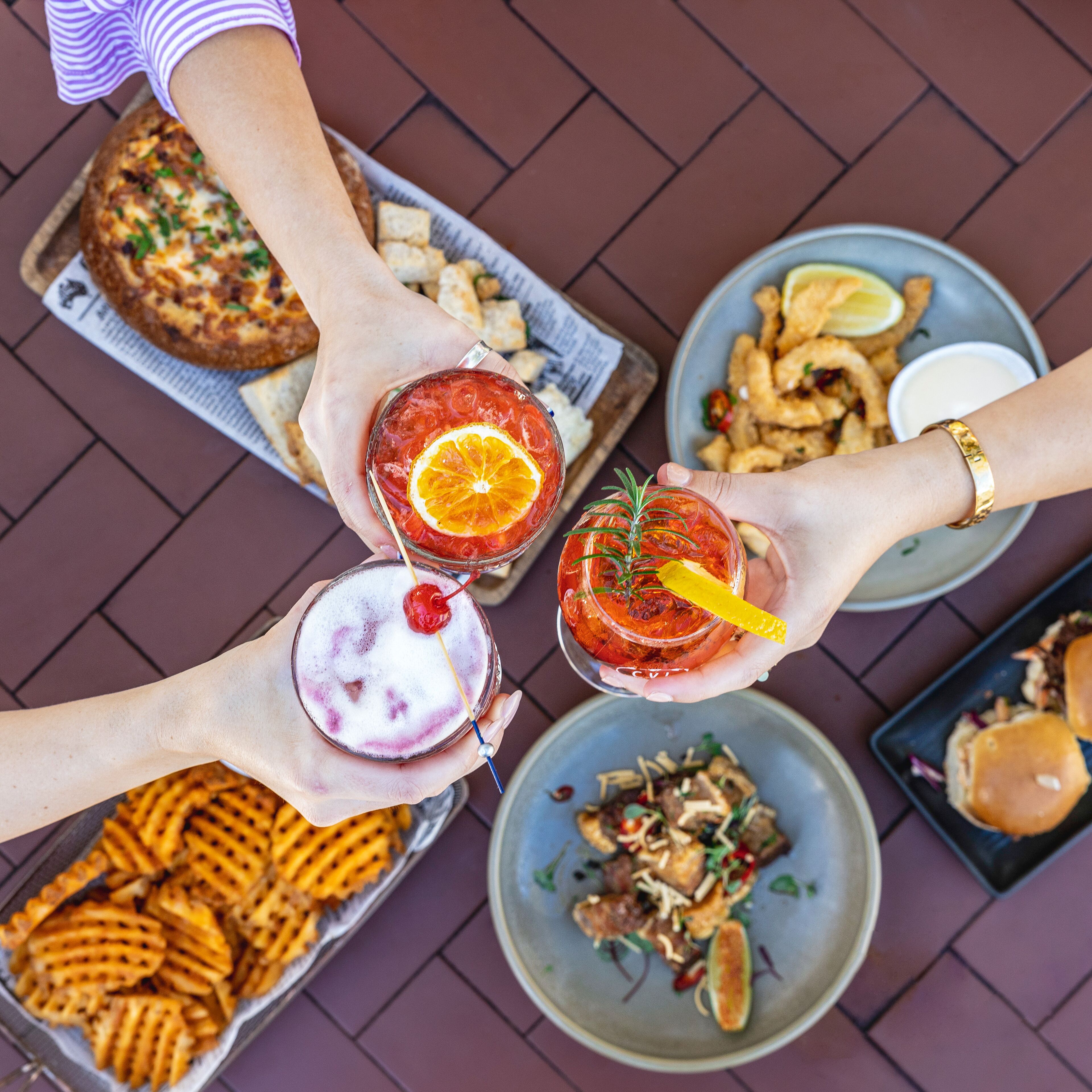Vue d’ensemble d’une table à manger, avec différents plats, notamment des gaufres, des aliments frits et une salade.