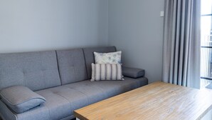 A modern living room with a grey sofa, two pillows, and a wooden coffee table. - Camden Valley Inn (Cawdor)