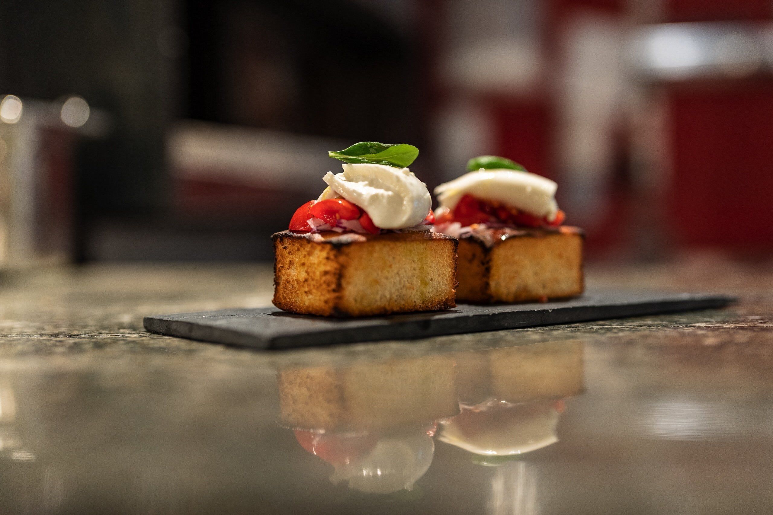 Zwei Toastscheiben mit Belag auf einer spiegelnden Fläche.