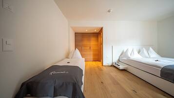 Een moderne hotelkamer met een houten vloer, een bed met wit beddengoed, een nachtkastje en een kledingkast.