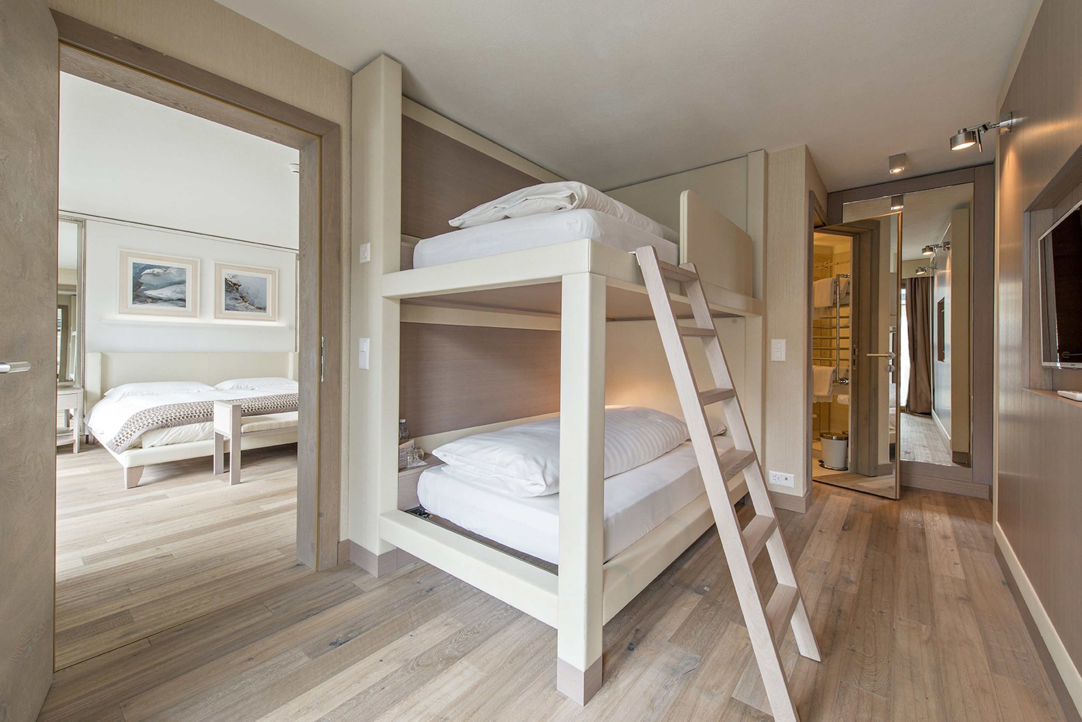 Habitación con literas de madera, una cama individual y un baño visible a través de una puerta abierta.