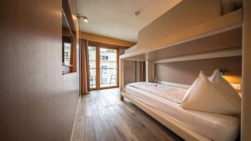 Ein modernes Hotelzimmer mit Holzboden, einem Bett mit weißer Bettwäsche und Blick auf Gebäude durch große Fenster.