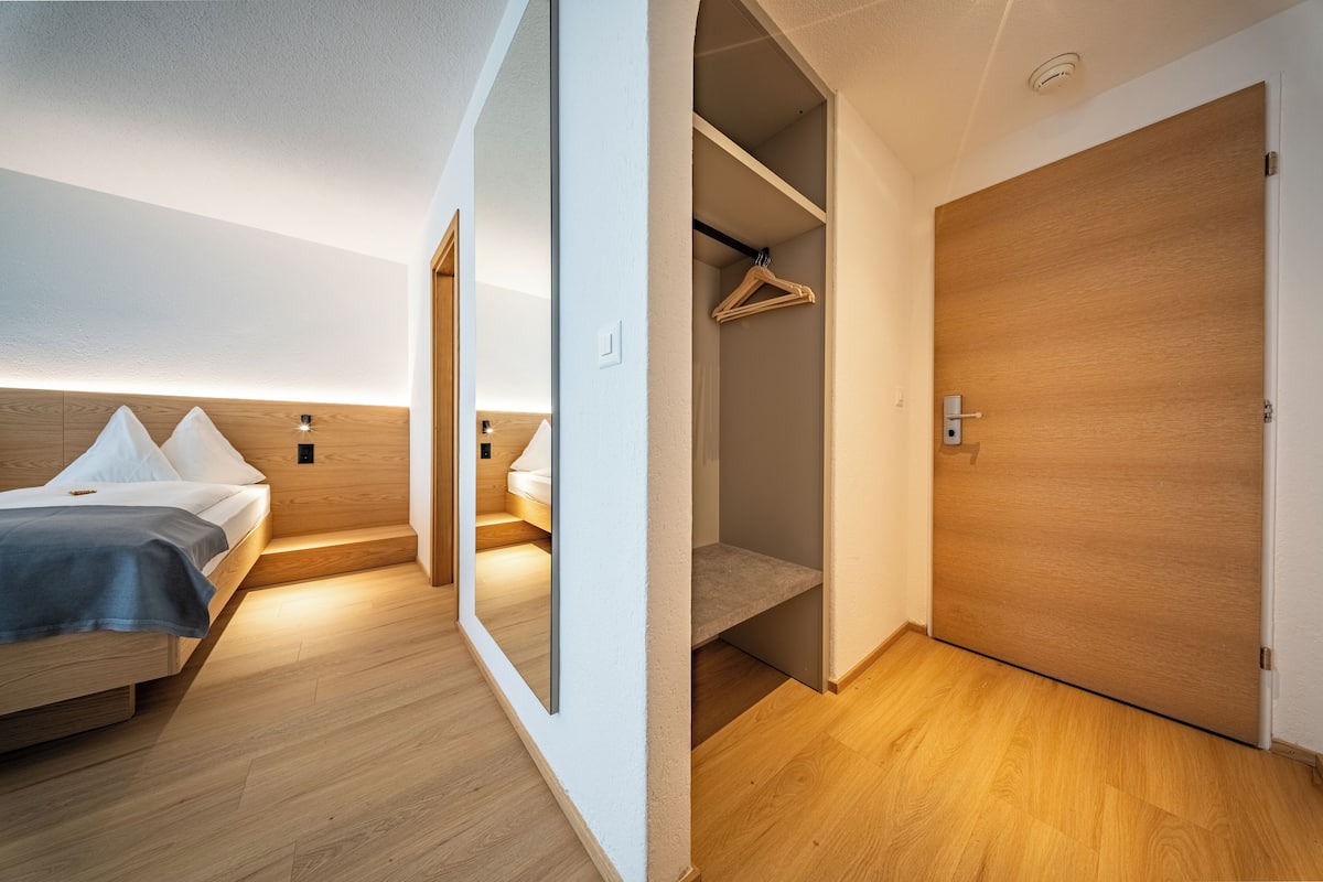 A modern bedroom with a bed, bedside table, and a wardrobe.