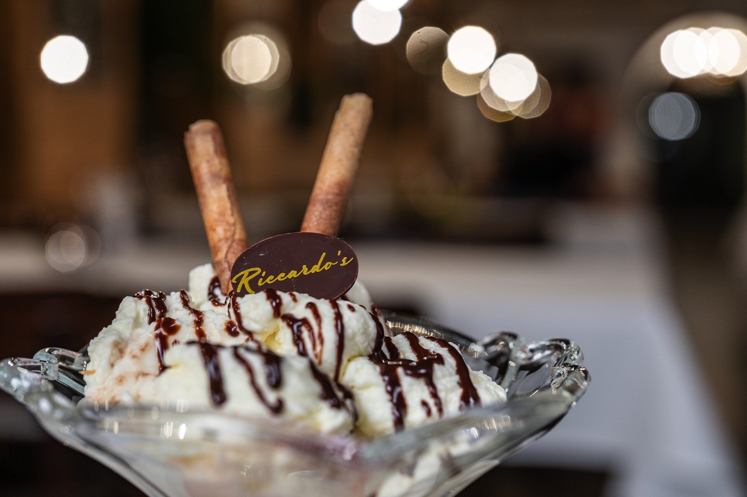 Uma sobremesa com bolas de sorvete cobertas com calda de chocolate e um pedaço de chocolate com a etiqueta 