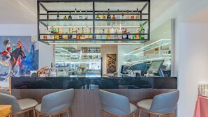 A bar area with a marble counter, multiple shelves of bottles, and a seating area with bar stools.