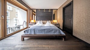 A modern hotel room with a large bed, a balcony, and a view of the city.