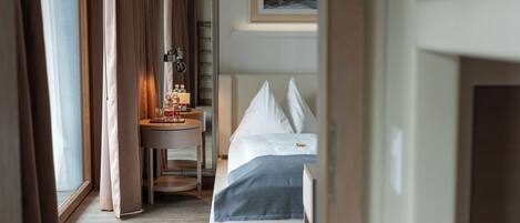 A hotel room with a bed, bedside table, and a window with curtains.