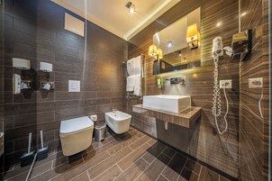 Uma casa de banho moderna com bidé, sanita, toucador e um espelho grande.