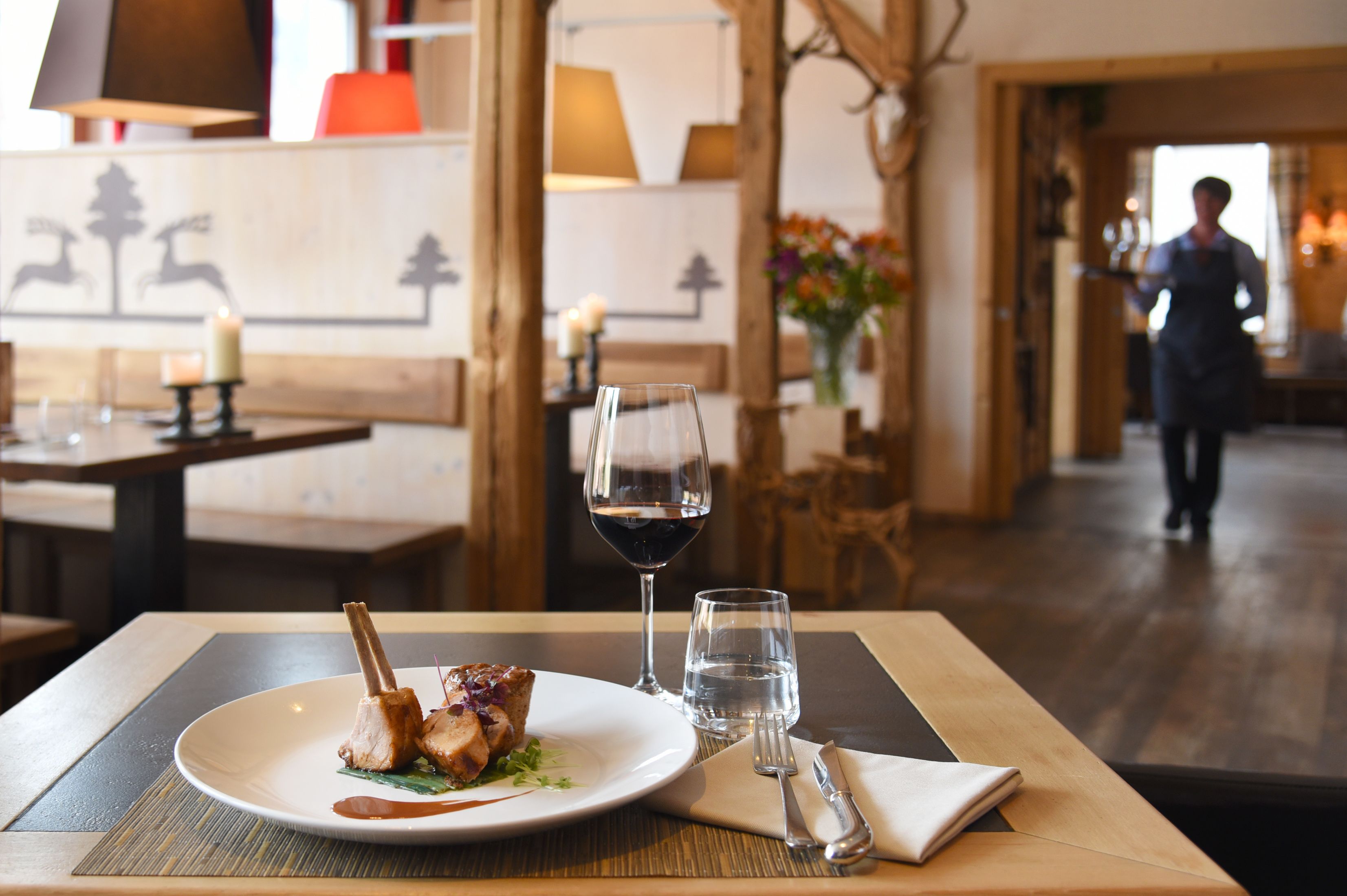 A dining table with a plate of food, a wine glass, and a water glass.