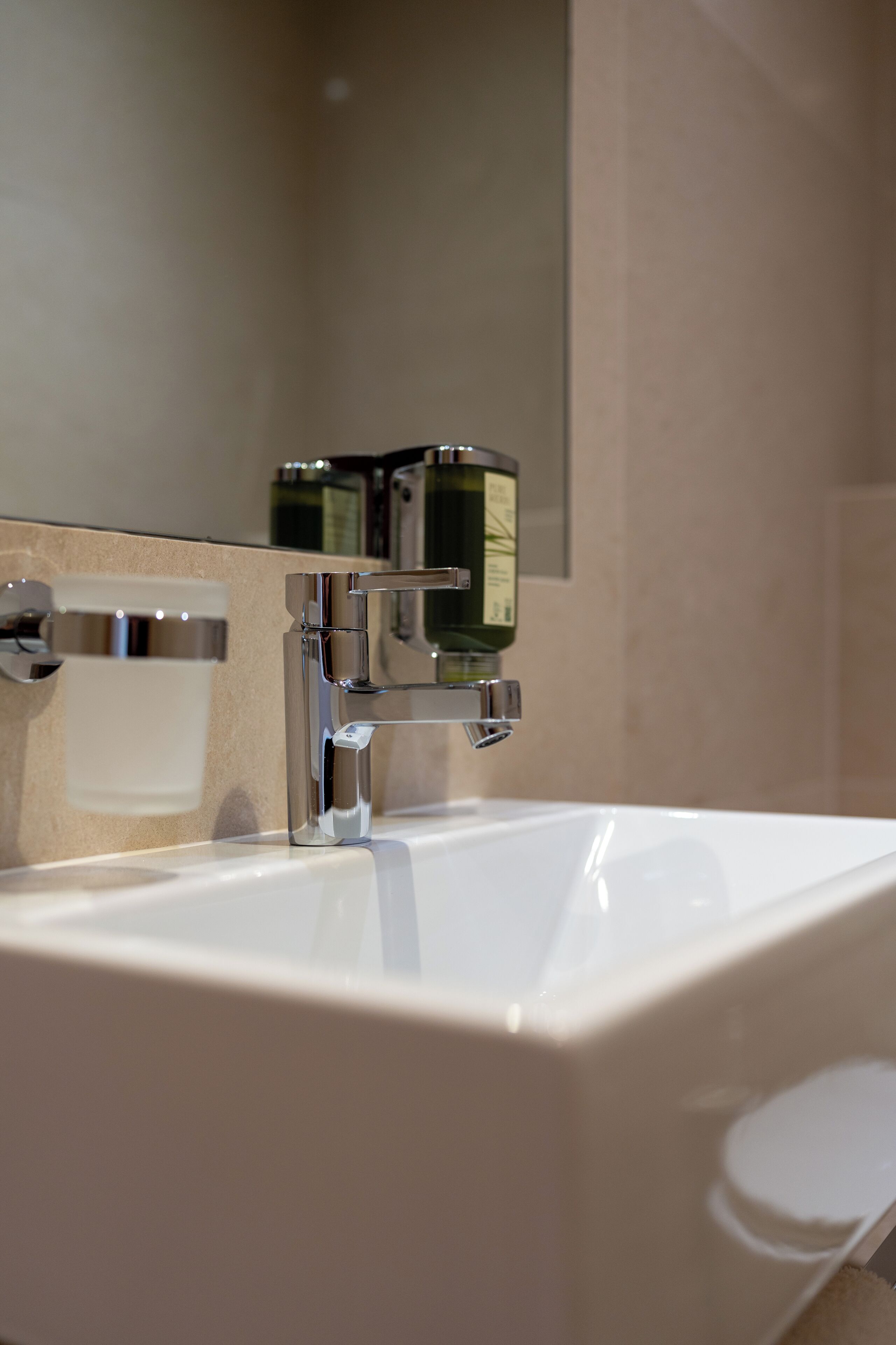 Un baño moderno con un grifo de cromo, un lavabo blanco y un espejo.