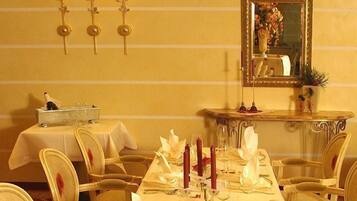 Ein eleganter Speisesaal mit langem Tisch, gedeckten Plätzen und einem Spiegel an der Wand.