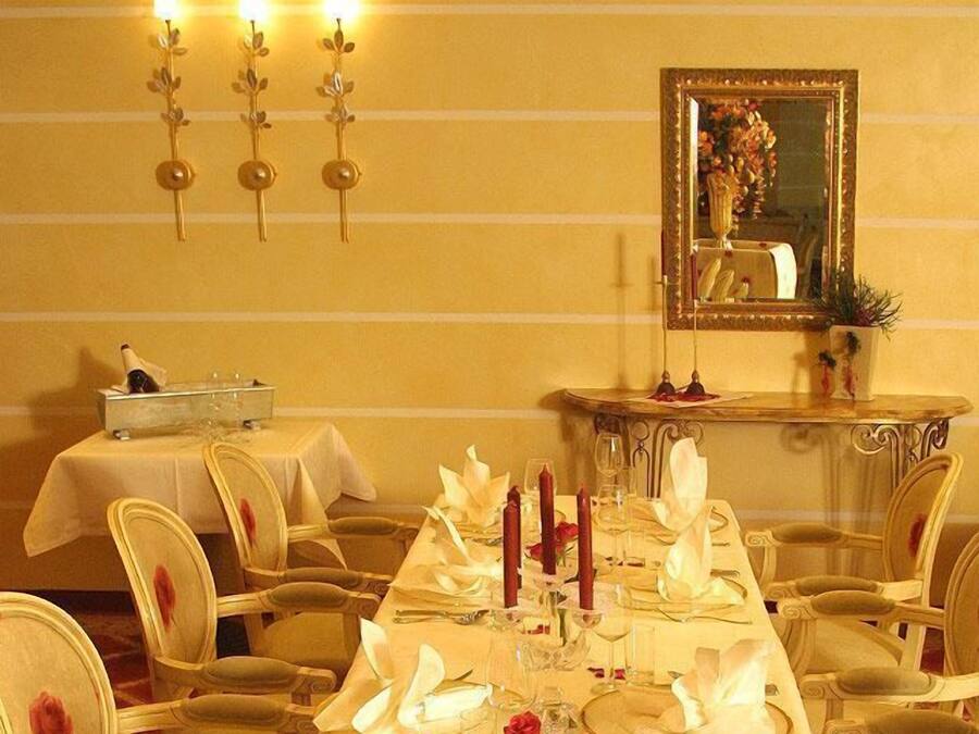 Ein eleganter Speisesaal mit langem Tisch, gedeckten Plätzen und einem Spiegel an der Wand.