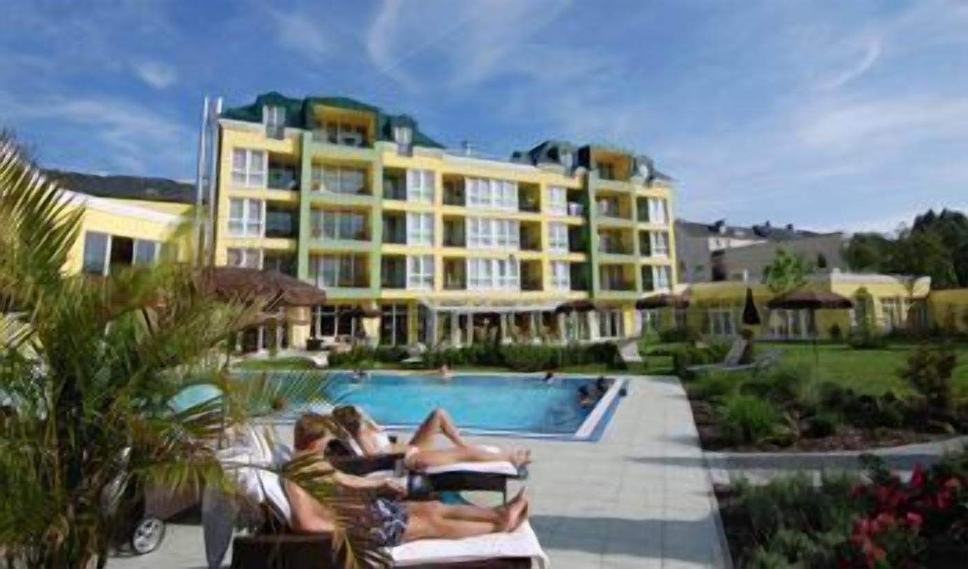 Un hotel con piscina, lettini e un giardino curato.