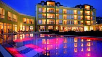 A multi-story hotel with a pool reflecting colorful lights.