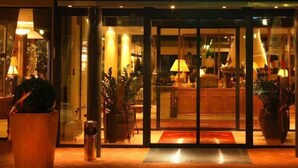 Ein Hotel Eingang mit Glastür, einer Rezeption und Topfpflanzen.