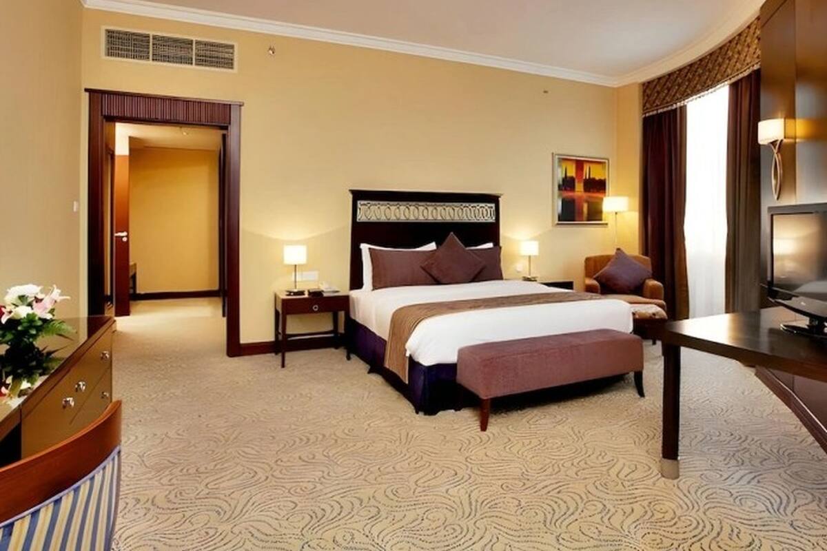 A hotel room with a large bed, bedside tables, a desk, and a TV.