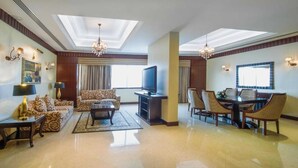 Un soggiorno spazioso con una TV a schermo piatto, divani decorati, un tavolino da caffè e una zona pranzo con sedie e tavolo.