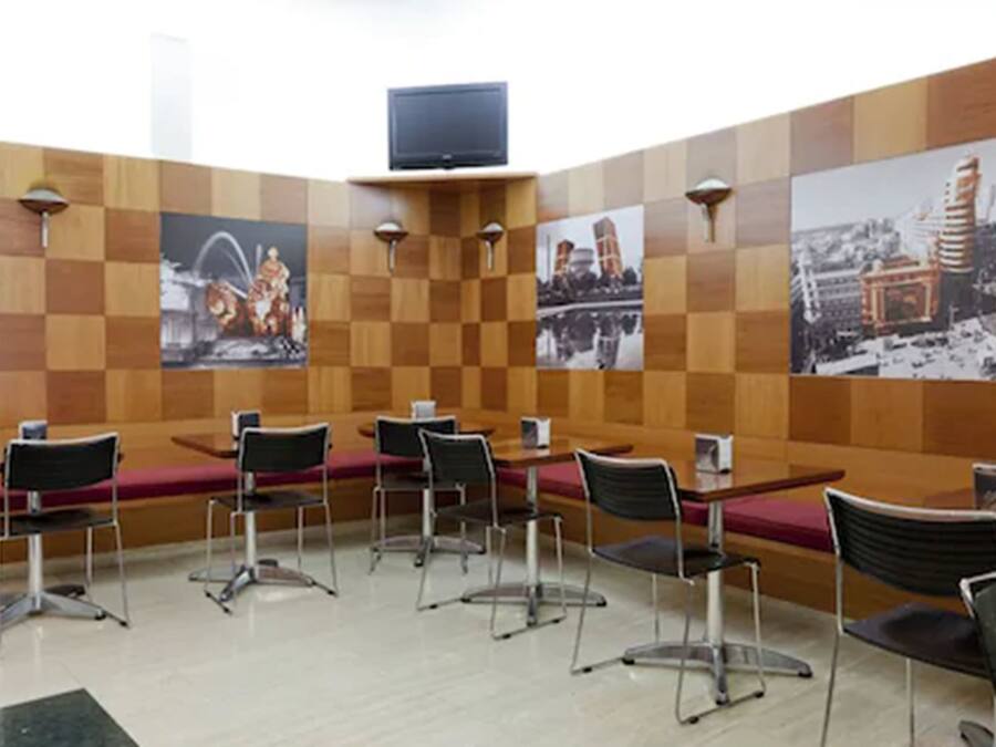 A conference room with a checkered wooden wall, a television mounted on the wall, and several tables with chairs.