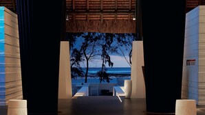 Un intérieur moderne avec un plancher en bois qui mène à un espace salon offrant une vue sur l’océan.