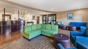 A lobby with a reception desk, green and blue sofas, a patterned carpet, and a framed picture on the wall. - Comfort Suites Blythe (Blythe)