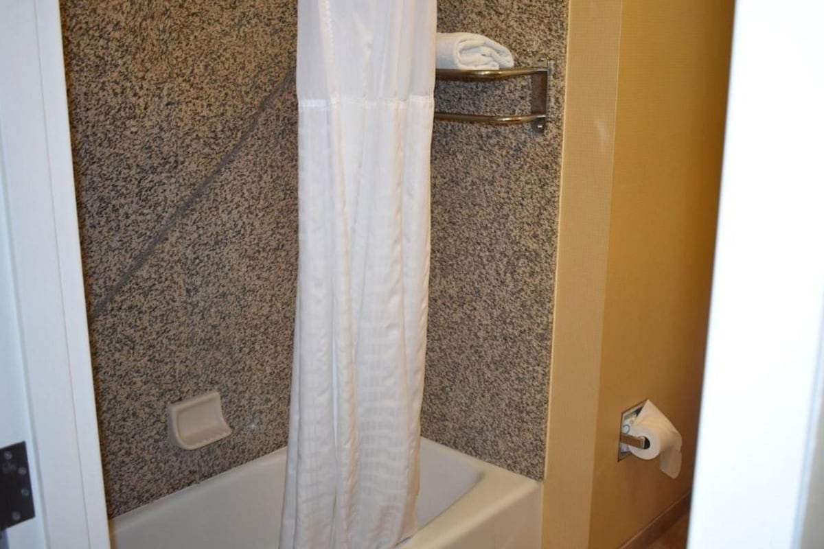 A bathroom with a shower curtain, a towel rack, and a toilet paper holder.