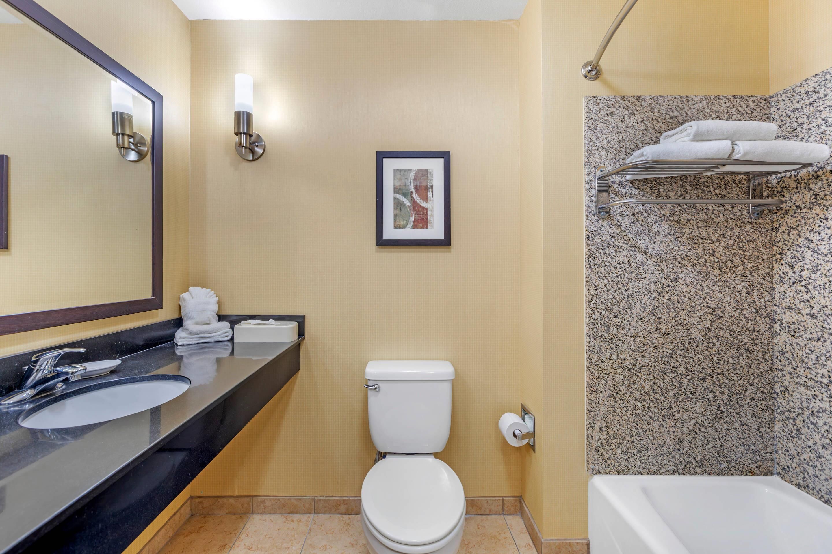 A bathroom with a sink, toilet, framed artwork, and a towel rack.