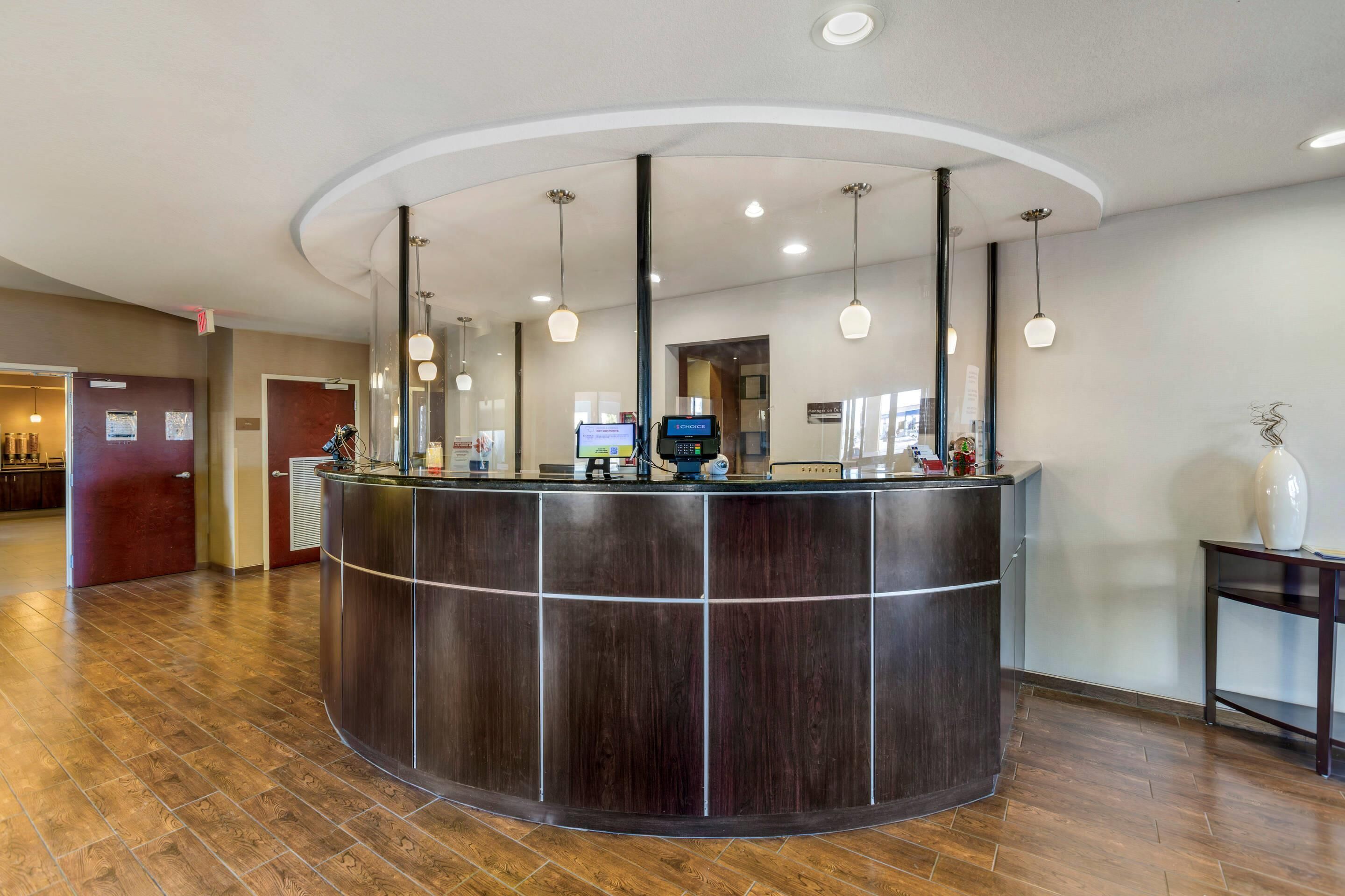 A reception desk with a curved design, overhead lighting, and a digital screen.