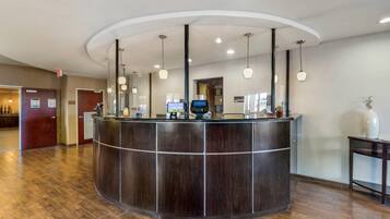 A reception desk with a curved design, overhead lighting, and a digital screen.