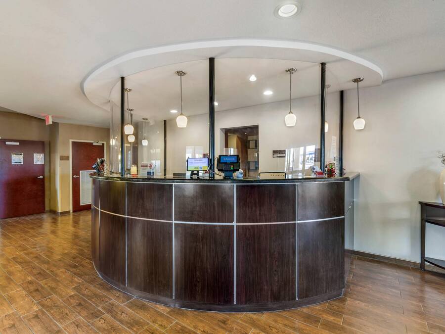A reception desk with a curved design, overhead lighting, and a digital screen.