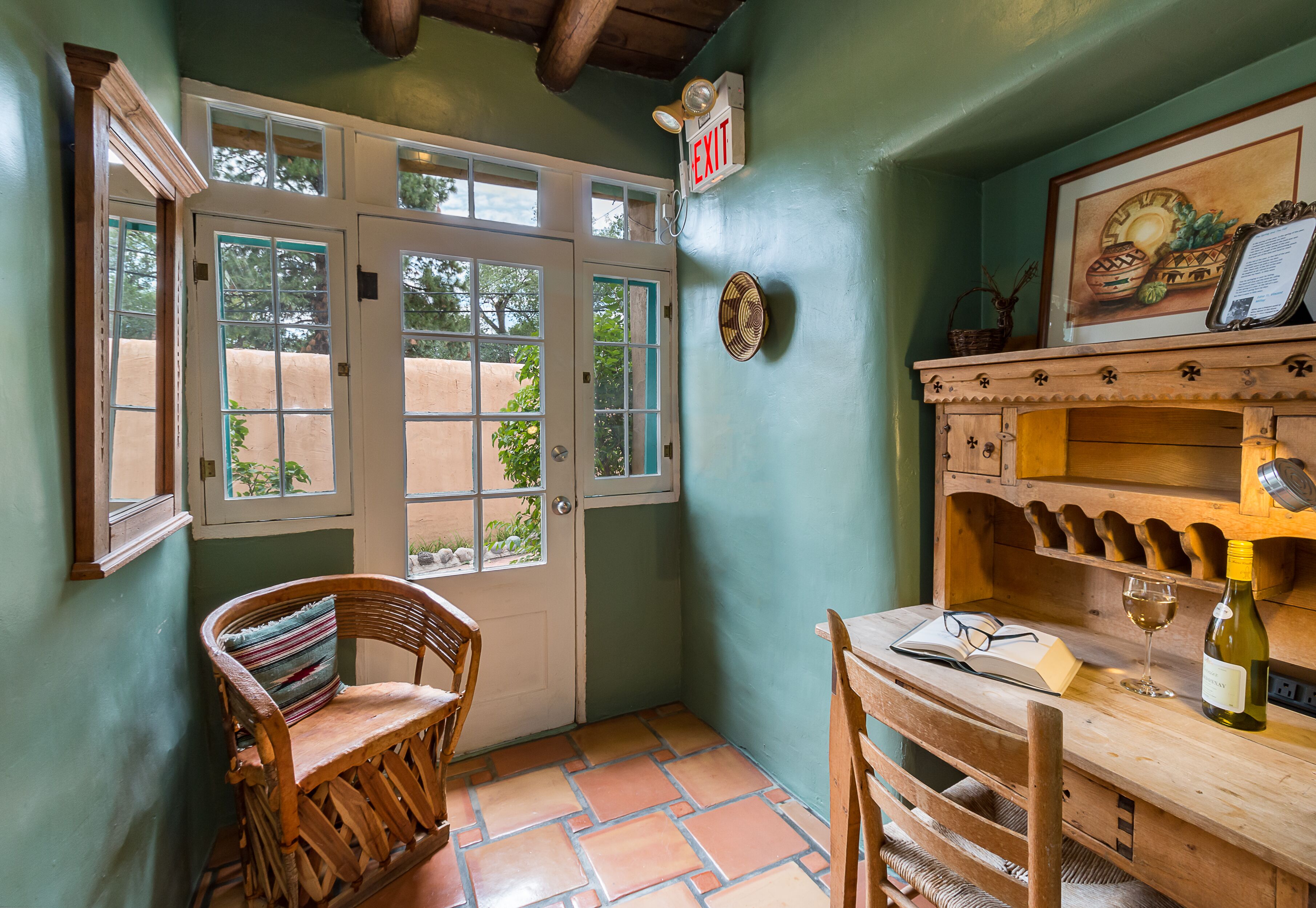 A cozy corner with a wooden table, a chair, a wine bottle, and a framed picture on the wall.