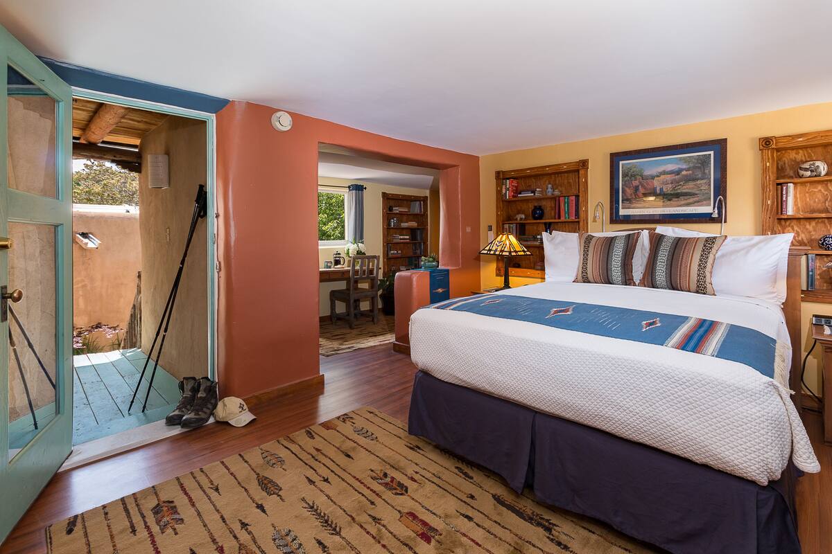 A bedroom with a bed, a rug, a bookshelf, and a door leading to an outdoor area.