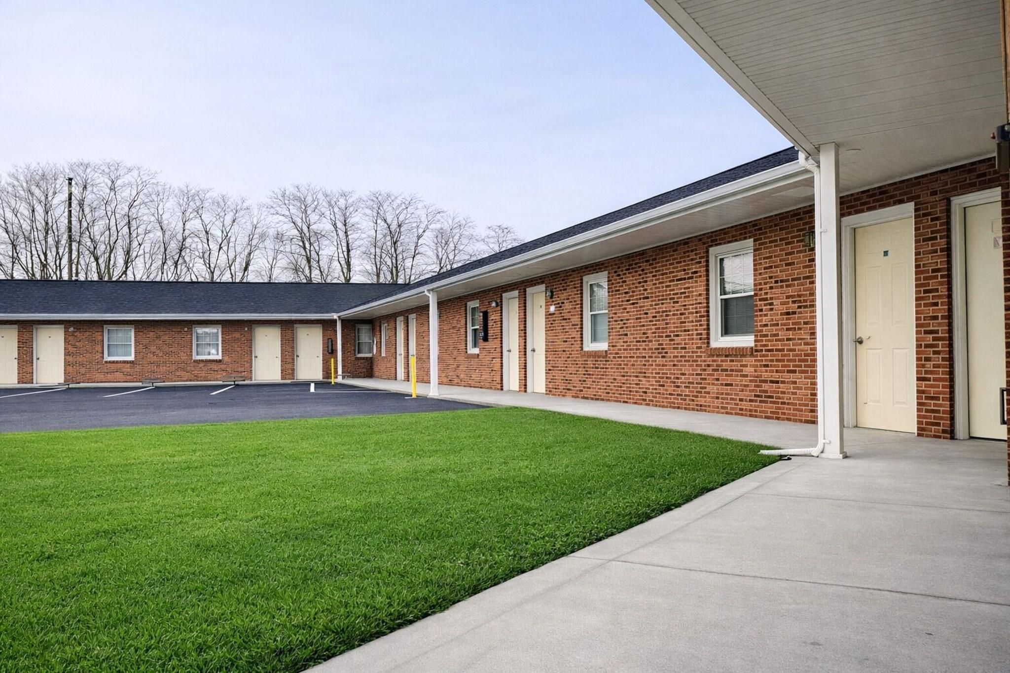 A building with a brick exterior, a covered parking area, and a well-maintained lawn.