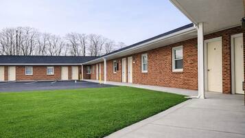 A building with a brick exterior, a covered parking area, and a well-maintained lawn.