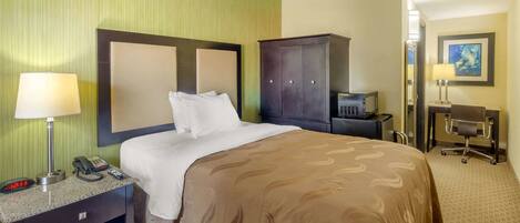 A hotel room with a bed, a desk, a chair, a wardrobe, and a telephone.