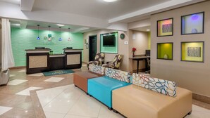 A hotel lobby with a reception desk, seating area, and decorative wall art.