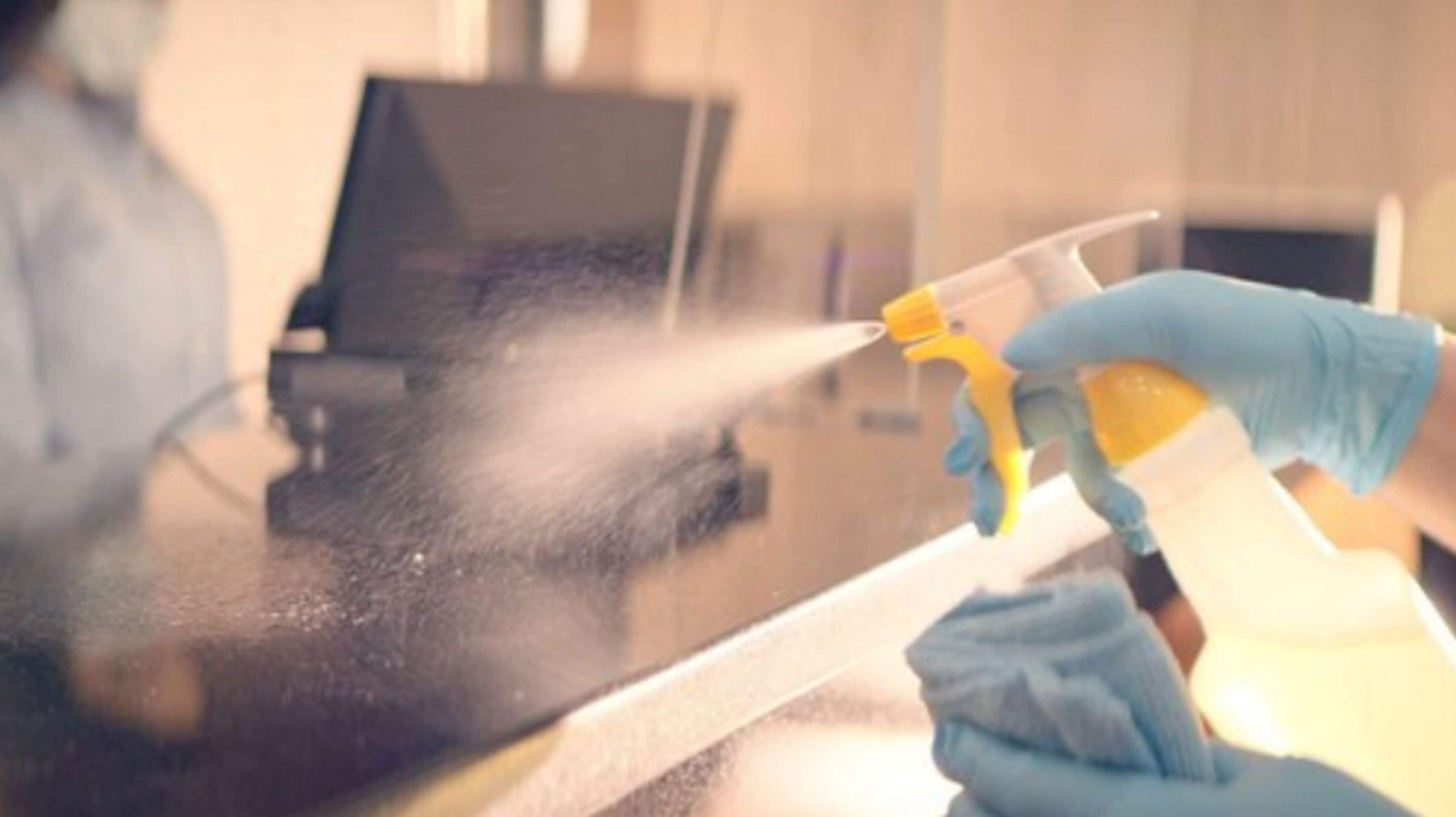 A person cleaning a glass surface with a spray bottle.