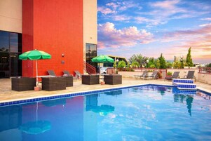 Una piscina al aire libre, sombrillas, sillones reclinables de piscina