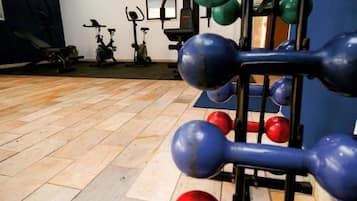 Uma academia com equipamentos de exercício, incluindo halteres e uma bicicleta ergométrica.