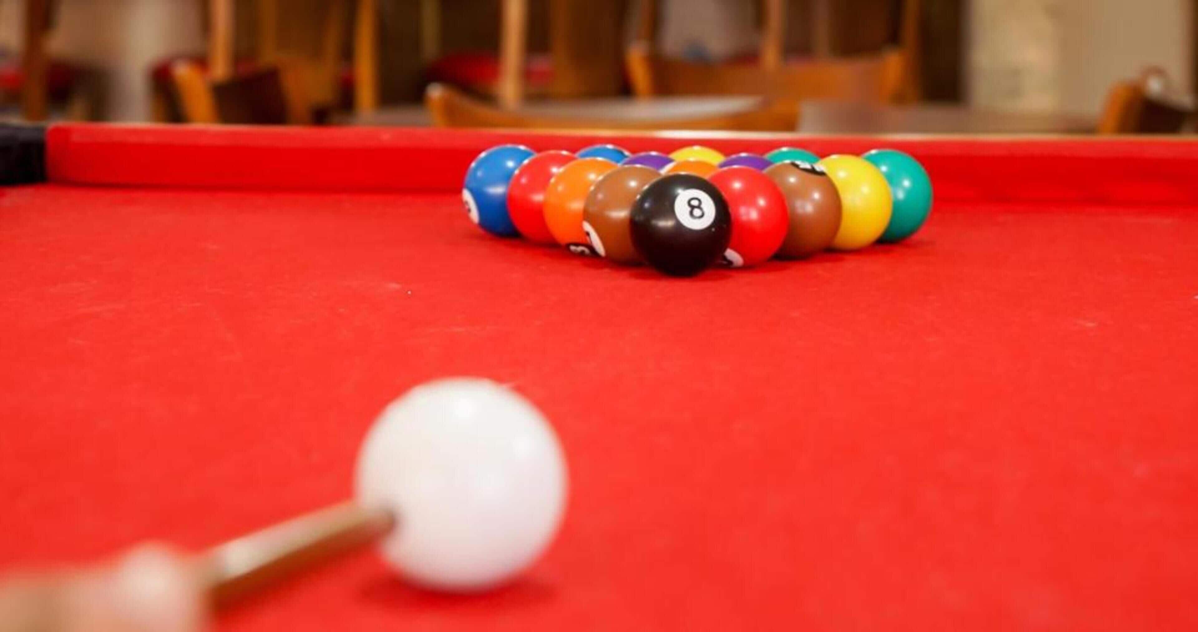 Une table de billard avec une boule blanche et des boules numérotées alignées.