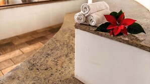 A spa area with a stone bench, rolled towels, and a potted plant.